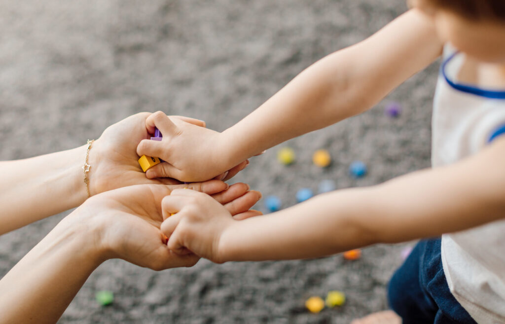 A parent holds both hands of a child.