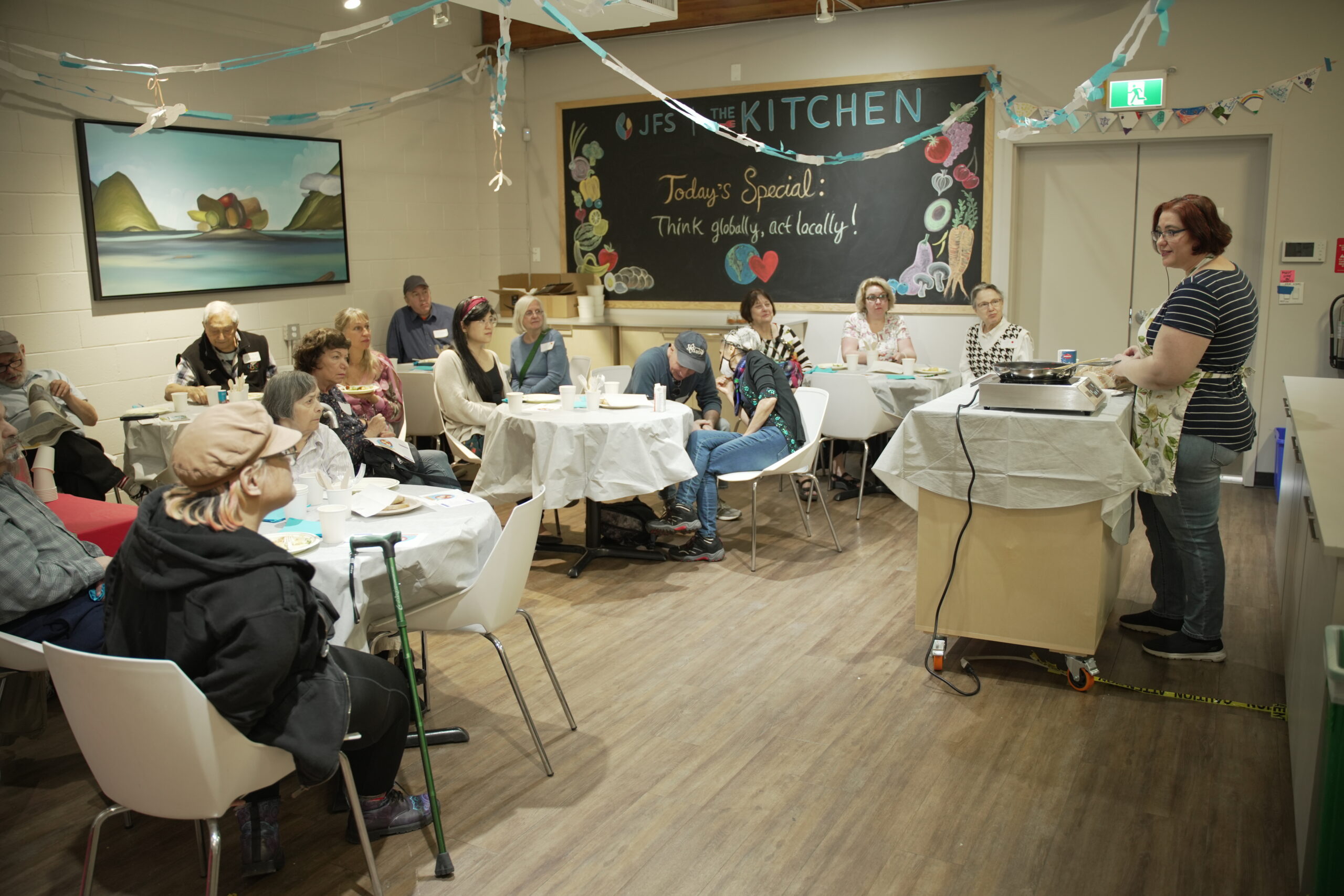 A person giving a live cooking demonstration to a room of people.