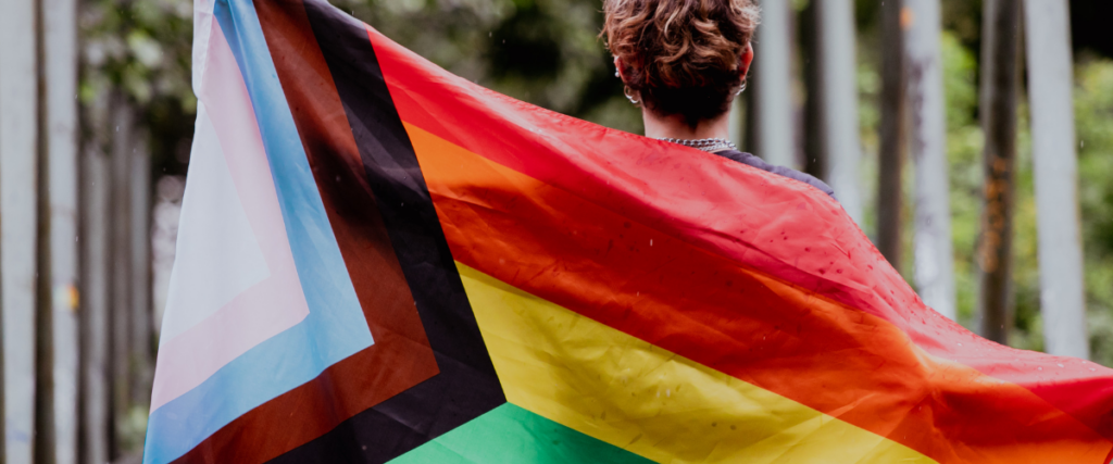 A person holding an LGBTQ2S+ flag