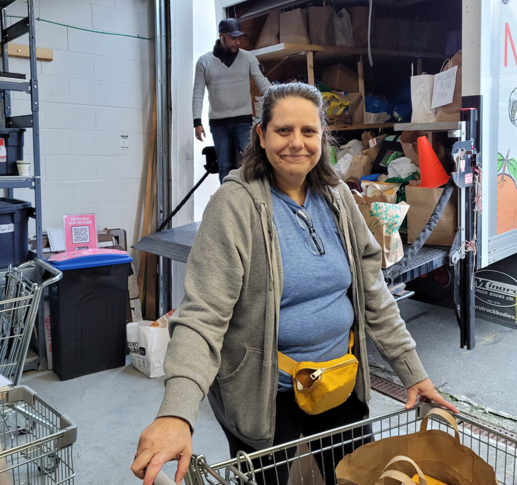 Staff member Carol pushes a cart loaded with donated food away from the JFS delivery truck.